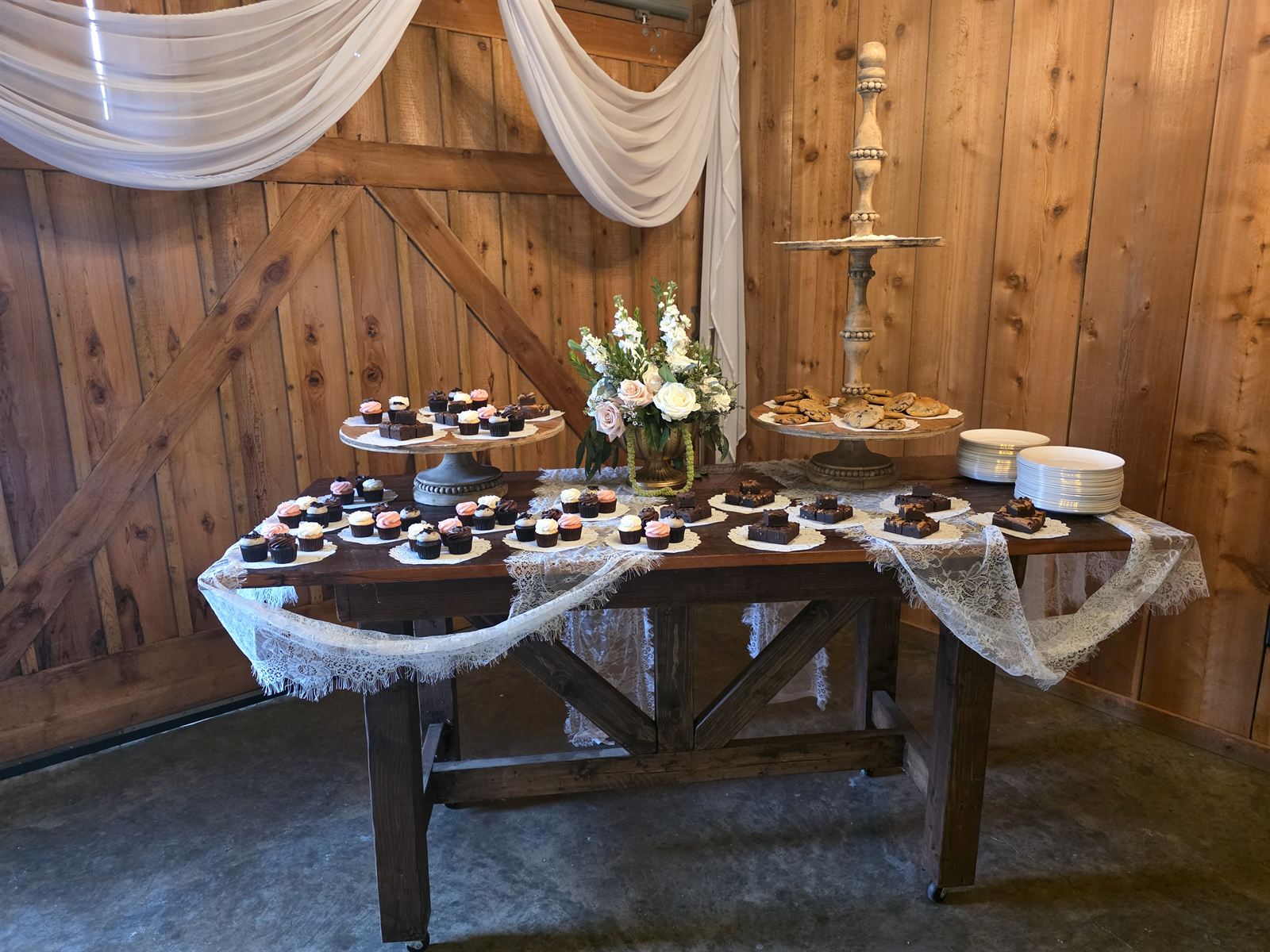 Dessert table with draped lace against the cedar barn wall
