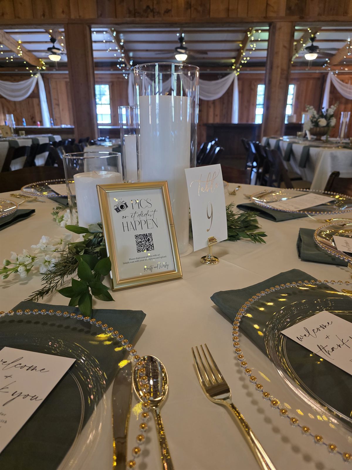 Reception place settings with gold flatware under the barn string lights